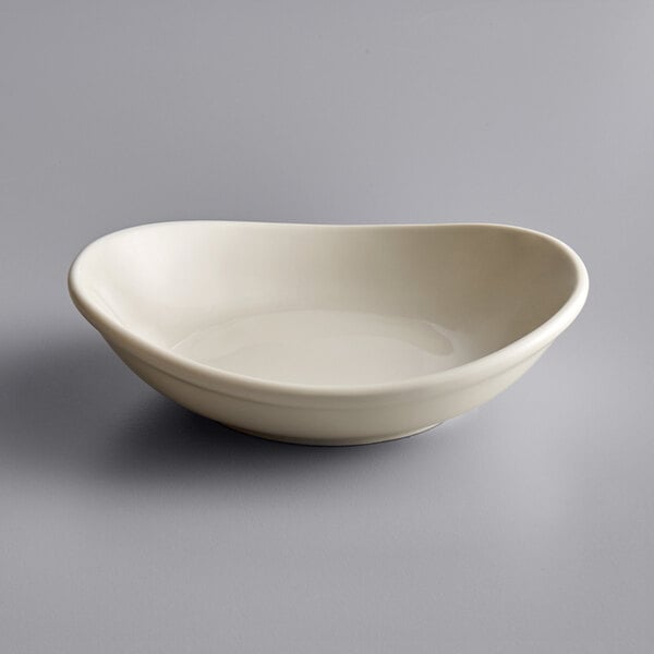 A close up of a Tuxton eggshell white china bowl with a curved edge.