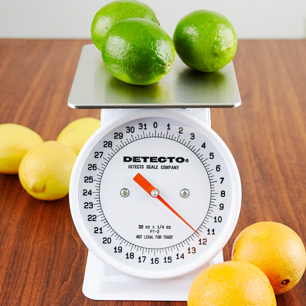 A Cardinal Detecto portion scale with limes on top and lemons on the counter.