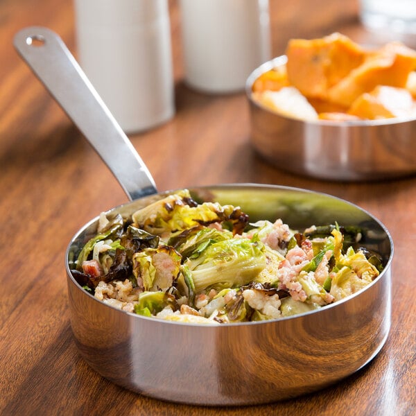 An American Metalcraft stainless steel pan of food on a table.