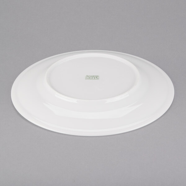 A white Arcoroc service plate with a green rim on a gray background.