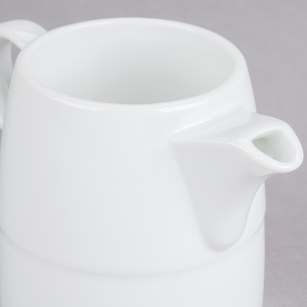 An Arcoroc white large creamer with a handle.