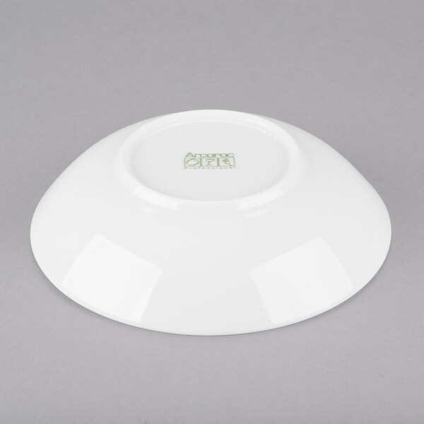A white Arcoroc coupe bowl with a green logo.