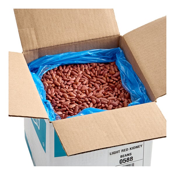 A large open cardboard box lined with a blue plastic bag, filled with dried light red kidney beans.