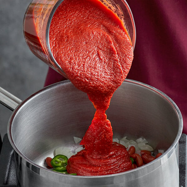 A person pouring Furmano's tomato puree into a pot.