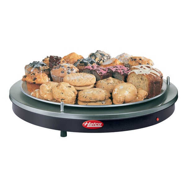 A plate of muffins and cupcakes on a black Hatco heated shelf.
