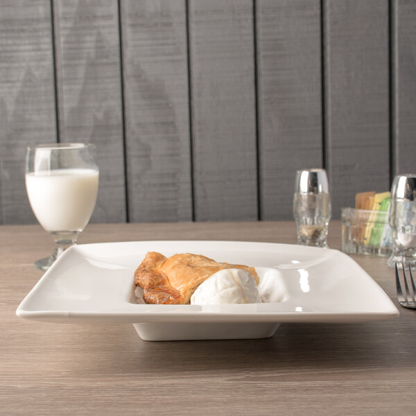 A plate of food in a 10 Strawberry Street Whittier white square wide rim bowl on a table.