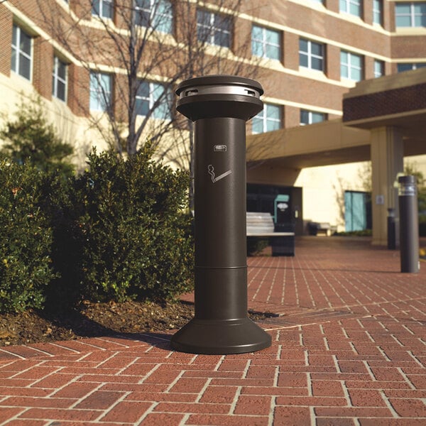 A Rubbermaid black cigarette receptacle on a brick walkway.