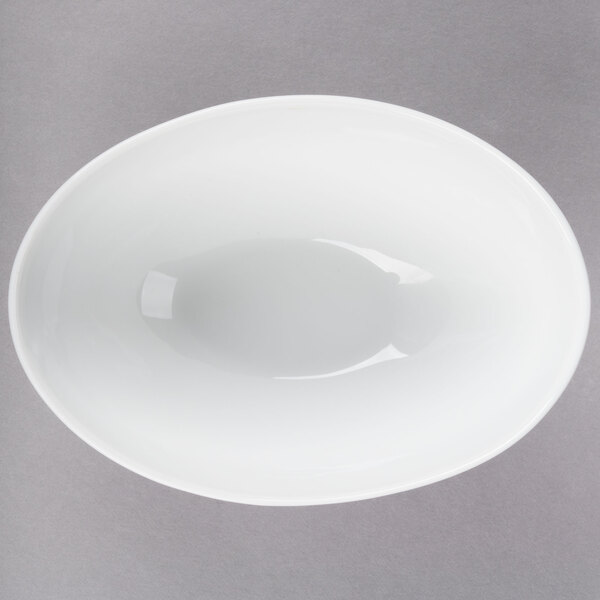 A white oval porcelain bowl with a small rim on a gray surface.