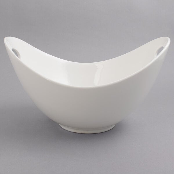 A white porcelain bowl with a curved edge and cut outs.