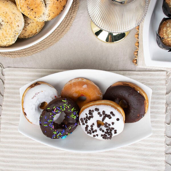 A rectangular white porcelain bowl filled with donuts on a table.