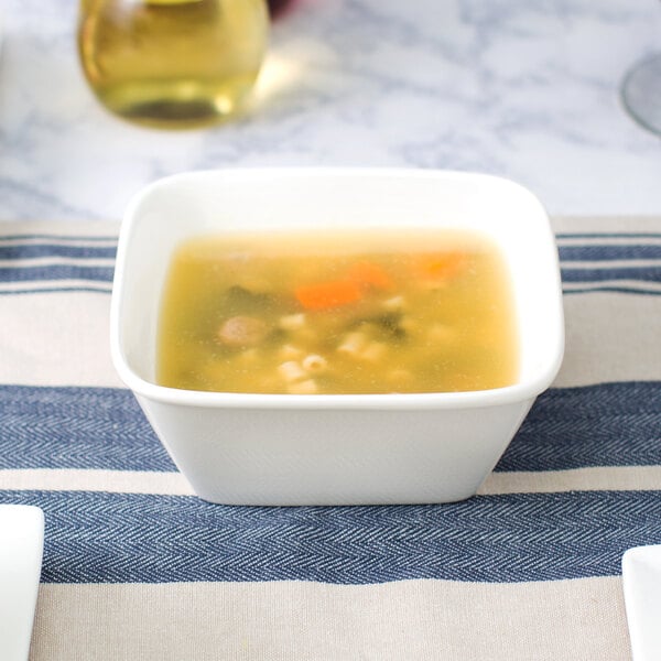 A 10 Strawberry Street Whittier white porcelain square bowl full of soup on a table.
