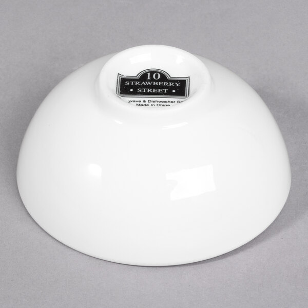 A white porcelain sauce dish with black text on it.