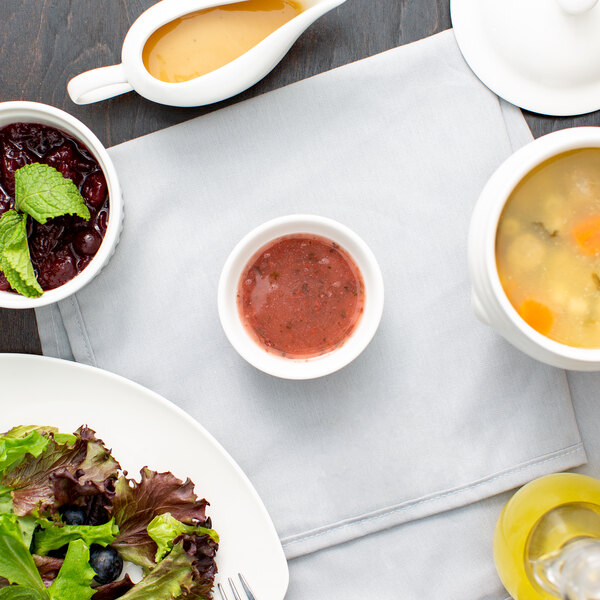 A table with 10 Strawberry Street white porcelain sauce dishes filled with yellow liquid.