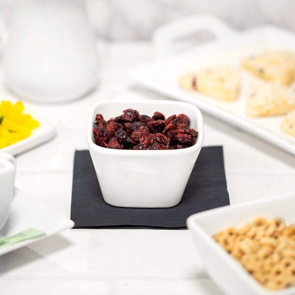 A white table set with 10 Strawberry Street Whittier white square porcelain bowls filled with cereal, nuts, and dried fruit.
