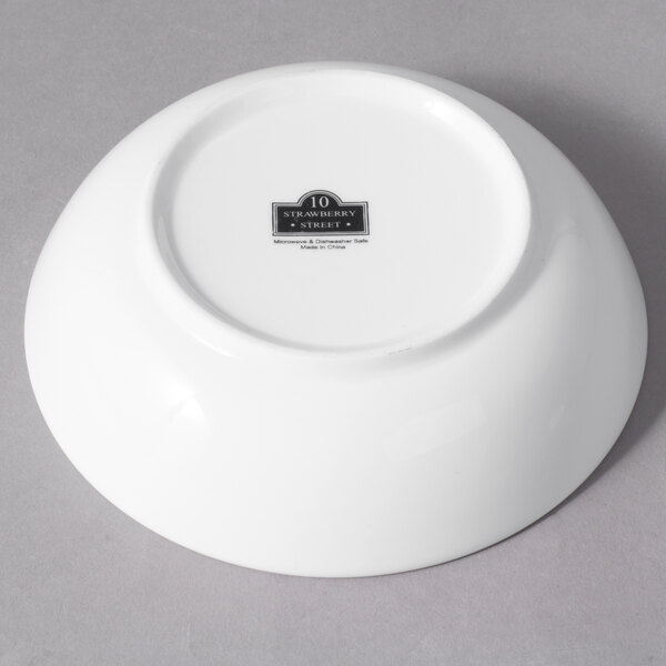 A white porcelain sauce dish with a black logo on it.