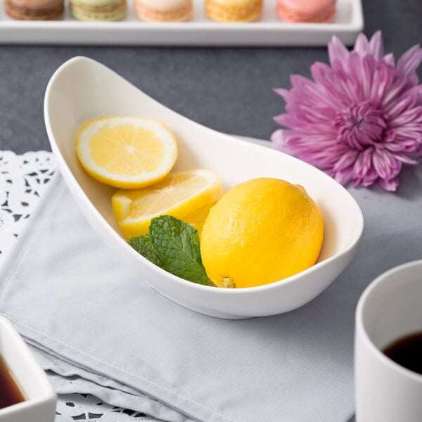 A white 10 Strawberry Street porcelain canoe bowl with lemons and mint inside.