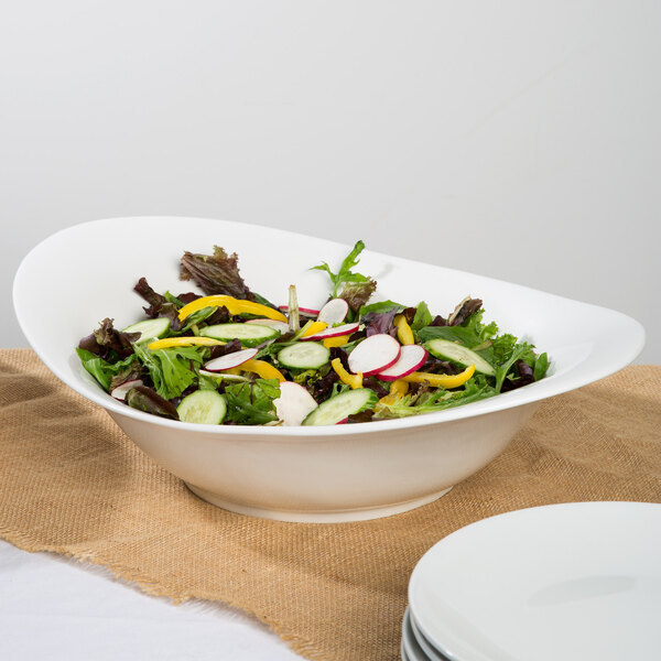 A bowl of salad with radishes and carrots in a white 10 Strawberry Street Whittier porcelain swoop bowl.