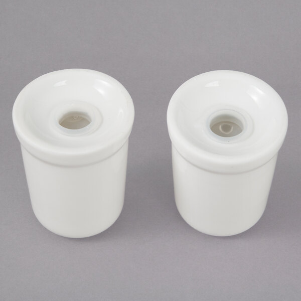 A pair of white porcelain salt and pepper containers with lids.