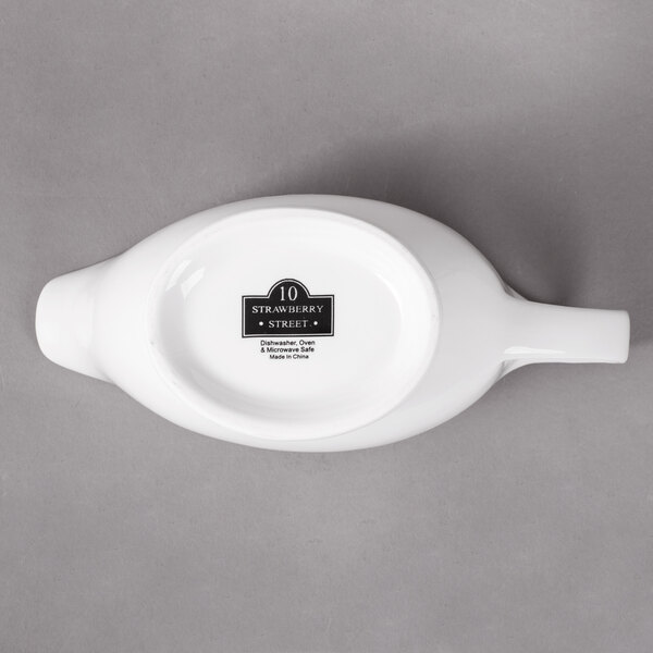 A white oval shaped porcelain gravy boat with a white background.