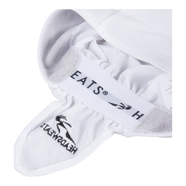 A close-up view of a white fabric cap with visible black embroidered logos and a Velcro strap.