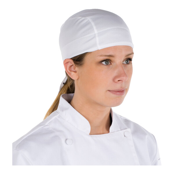 A person wearing a white chef's jacket and a white fitted cap, shown from the shoulders up against a plain background.