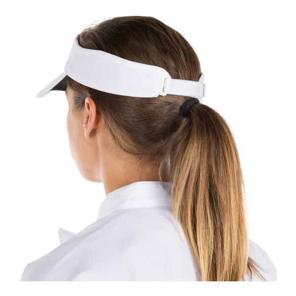 A person with long brown hair in a ponytail is wearing a white visor and a white collared shirt, viewed from the back.