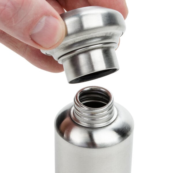 A hand holding a stainless steel American Metalcraft salt and pepper shaker set.