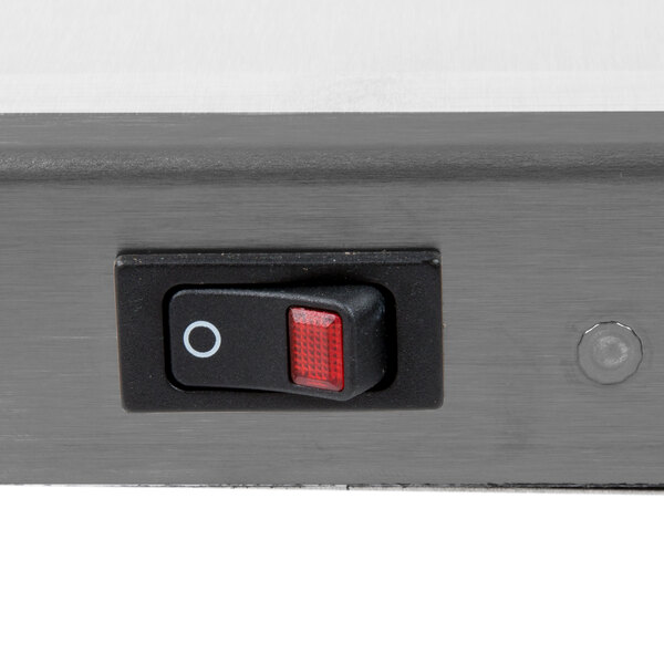 A close up of a red switch on a metal surface.