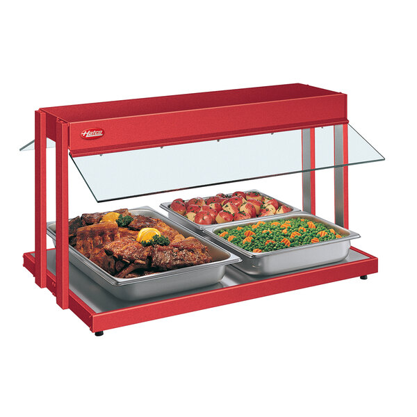 A Hatco red buffet warmer with trays of food including meat, peas, and carrots.