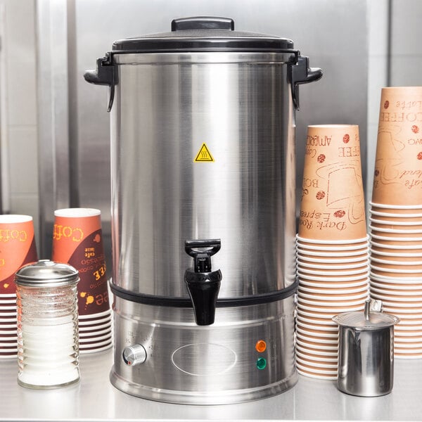 A Town 10 liter water boiler on a counter with coffee cups and a container of paper cups.