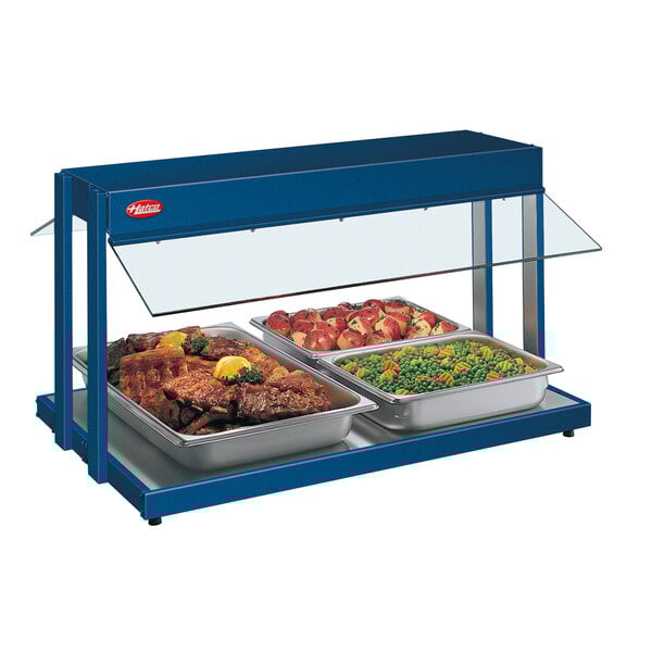 A navy blue Hatco buffet warmer with trays of food including meat and lemon wedges.