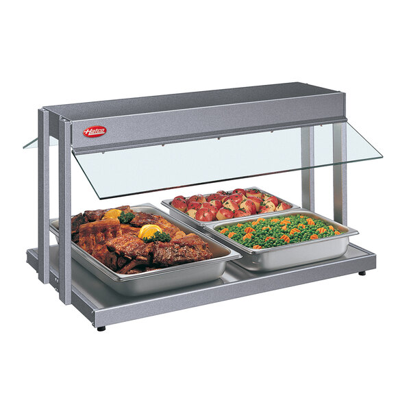 A Hatco countertop buffet warmer with trays of meat and vegetables on a table.