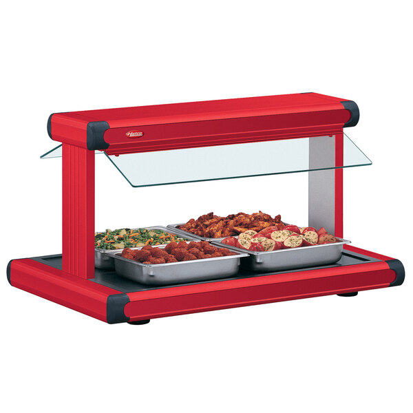A Hatco red food warmer holding red trays of food on a countertop.