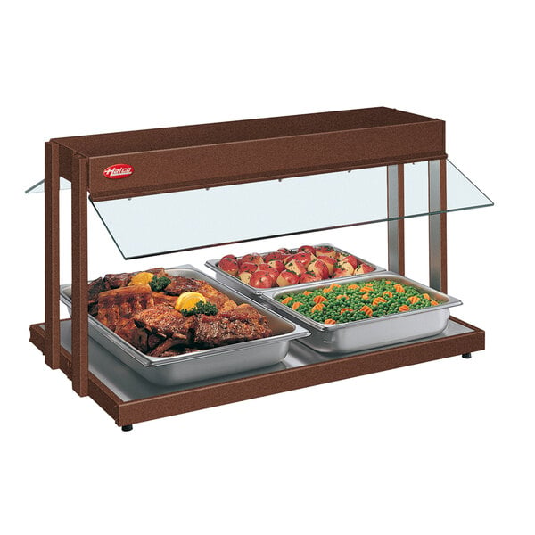 A Hatco buffet warmer with trays of meat and vegetables and peas and carrots on a table.