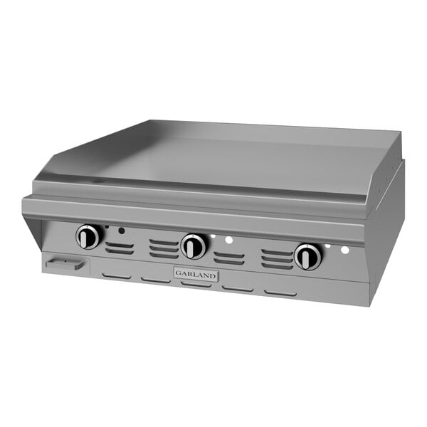 A stainless steel modular top griddle with manual controls designed for commercial cooking.