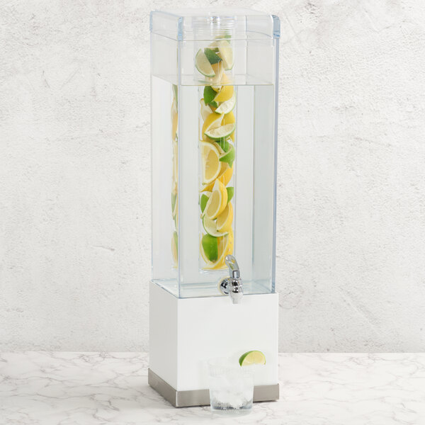 A tall, square stainless steel beverage dispenser with an infusion chamber filled with lemon and lime slices.