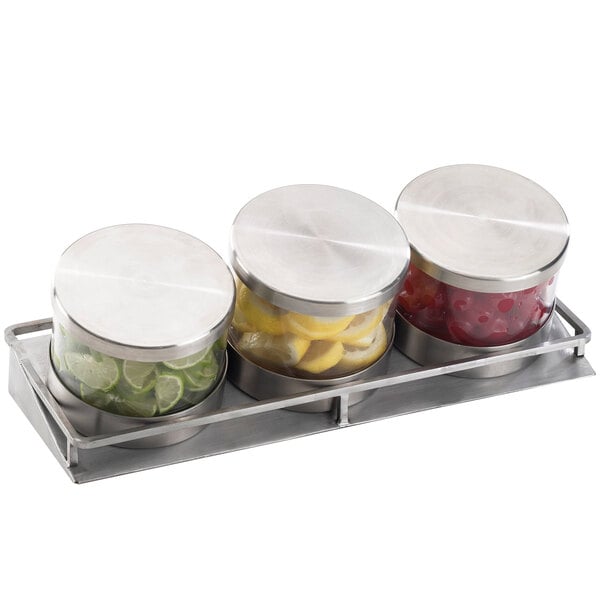 A Cal-Mil stainless steel horizontal display with three glass jars and metal lids containing fruit.