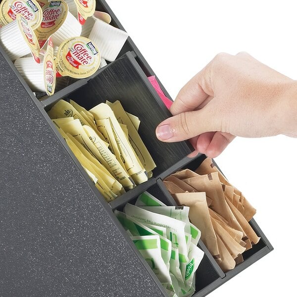 A hand using a Cal-Mil Classic Black Stir Stick and Condiment Display to get coffee condiments.