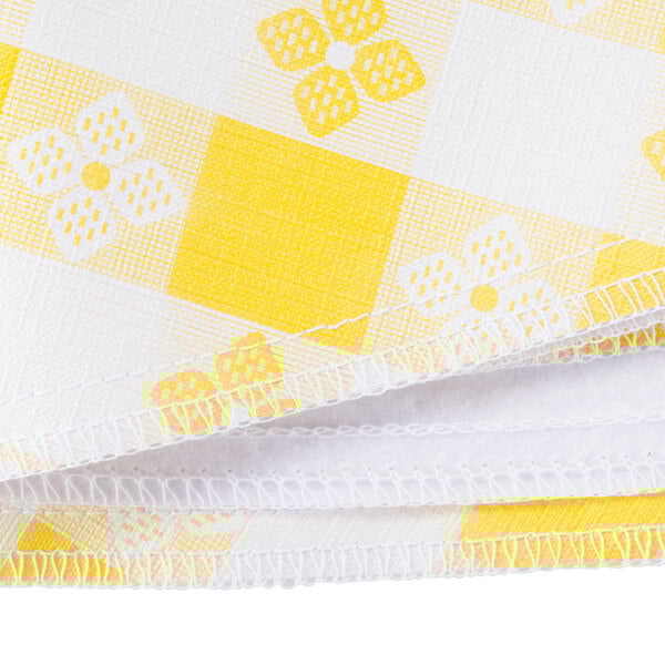 A close up of a yellow and white checkered vinyl table cover with a crochet pattern.