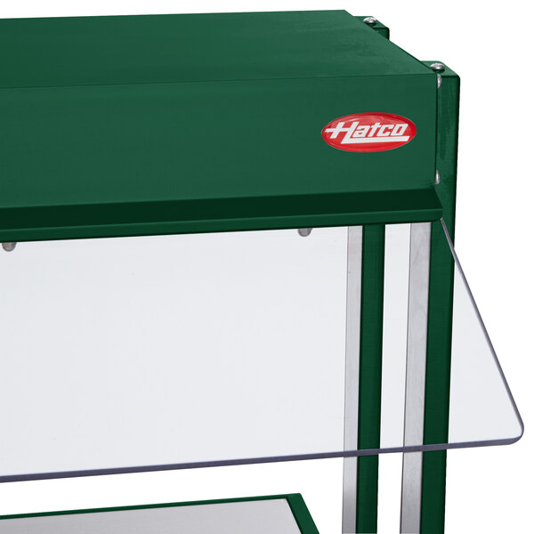 A green glass shelf with a clear top on a Hatco buffet warmer.