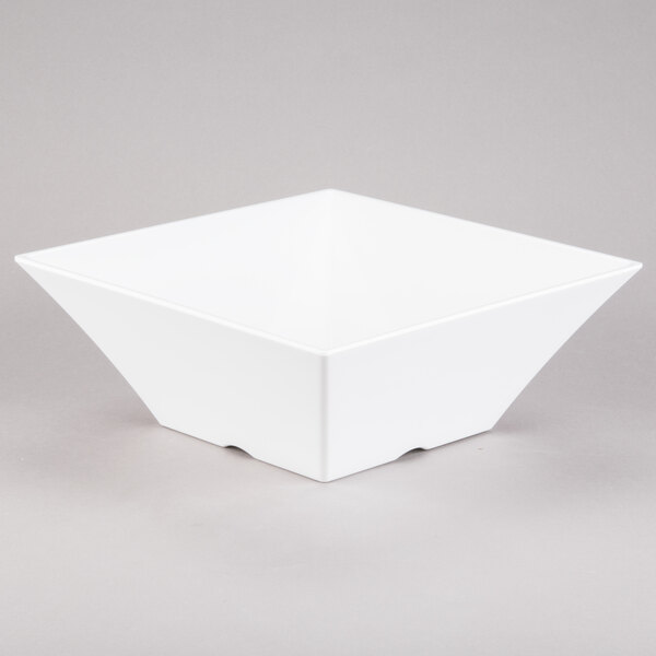 A white square Tablecraft melamine bowl with a corner on a gray surface.