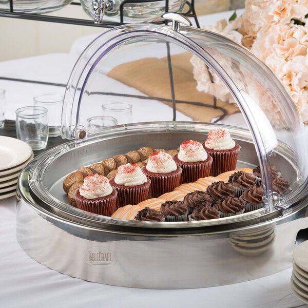 A Tablecraft CaterWare cold server on a table with cupcakes and cookies under a glass dome.