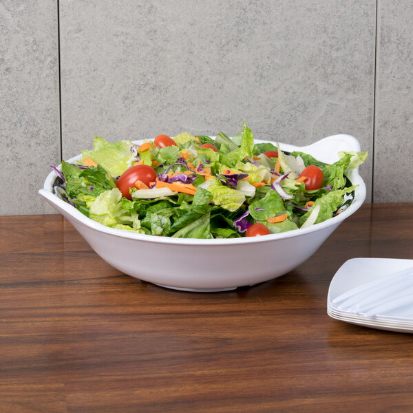 A Soho bowl filled with salad with tomatoes and lettuce on a table.