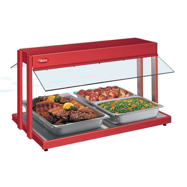 A Hatco red countertop buffet warmer with trays of food including peas and carrots and meat.