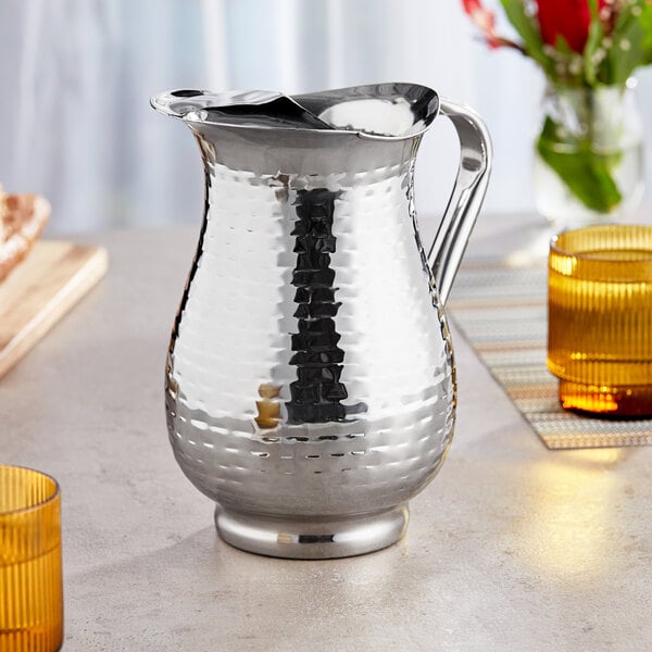 A Tablecraft stainless steel pitcher with a handle on a table.