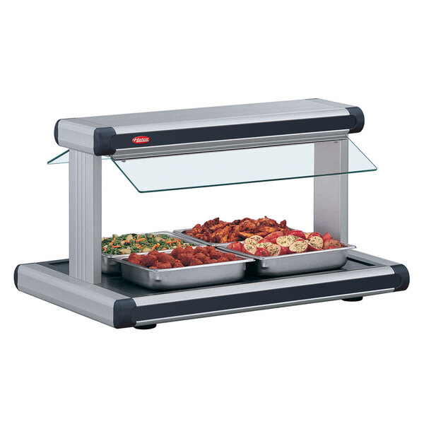 A Hatco buffet warmer with black insets on a countertop food buffet with a glass top.