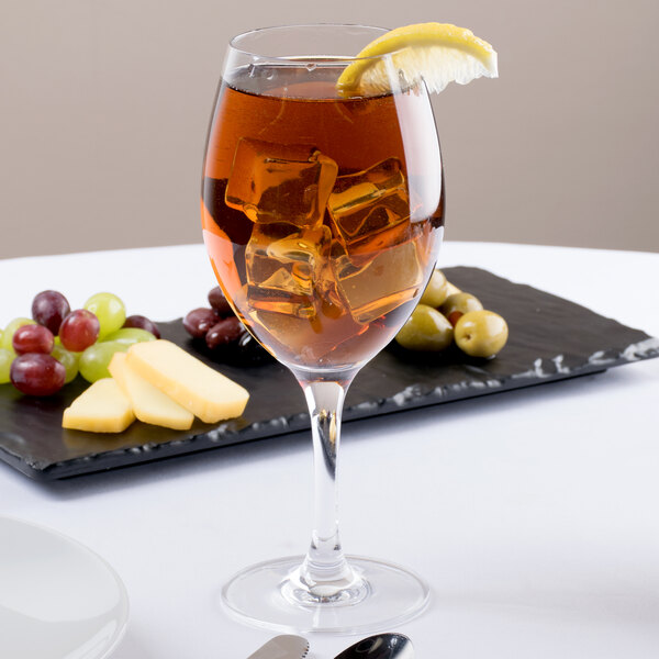 A Stolzle Bordeaux wine glass with ice and a lemon wedge in it.