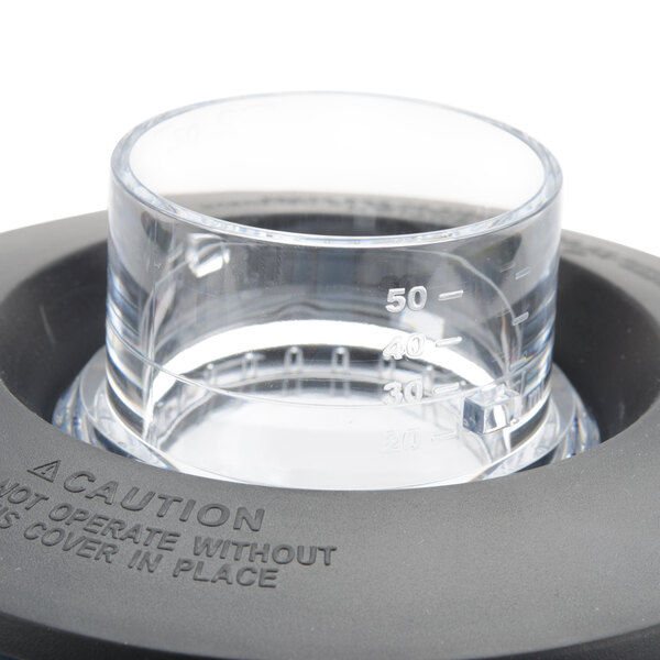The clear fill cap for a Hamilton Beach commercial blender on a table in a cocktail bar.