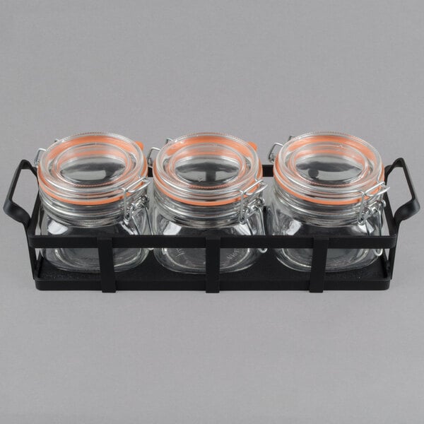 A black metal tray holding three glass jars with black lids.