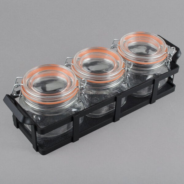 A group of glass jars in a black metal holder.